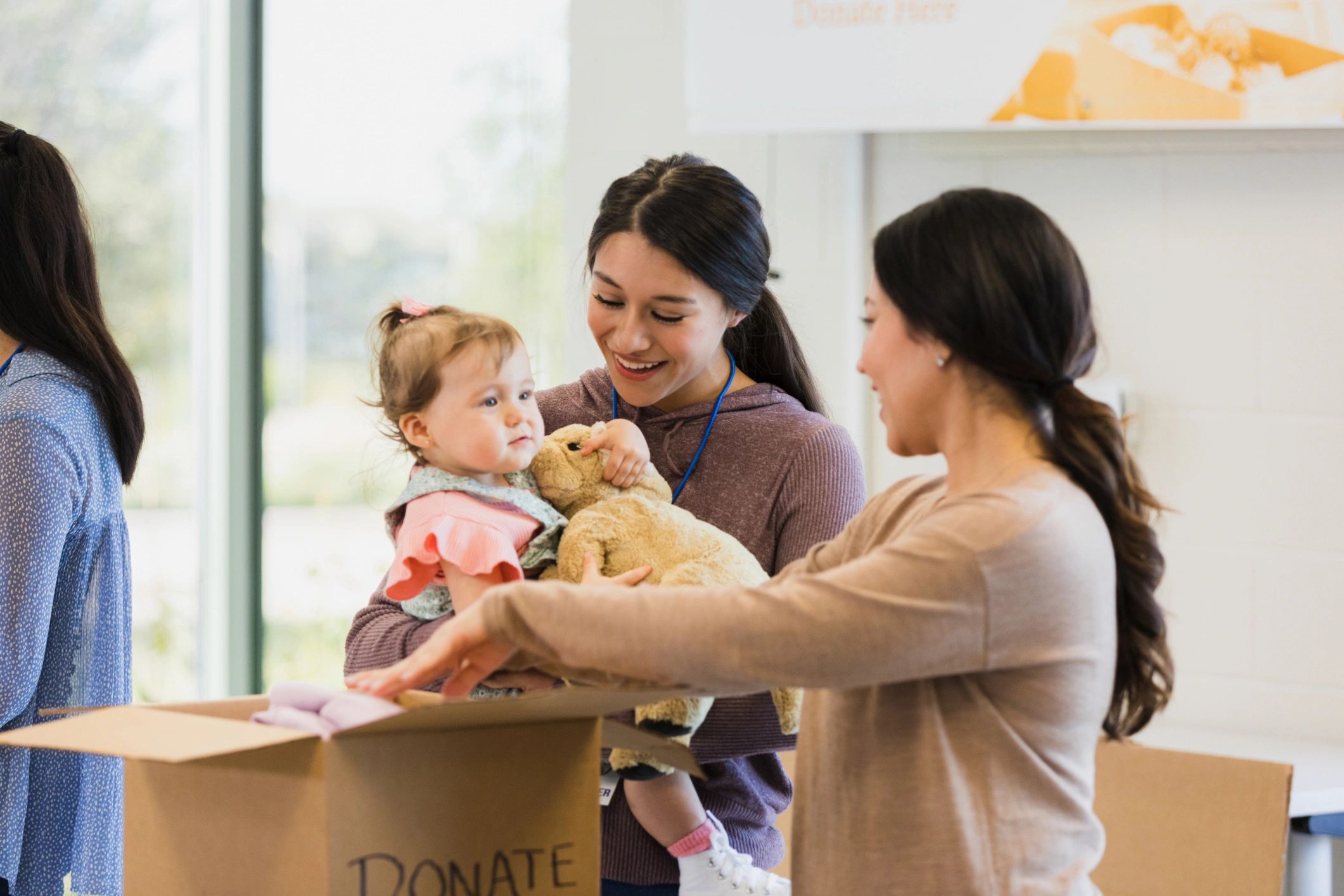 Volunteer carrying a child while helping at a community clothing drive